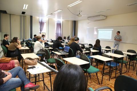 Sala de aula com um estudante apresentando para alunos na sala