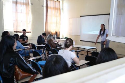 Estudante fala para uma turma de alunos em um sala de aula